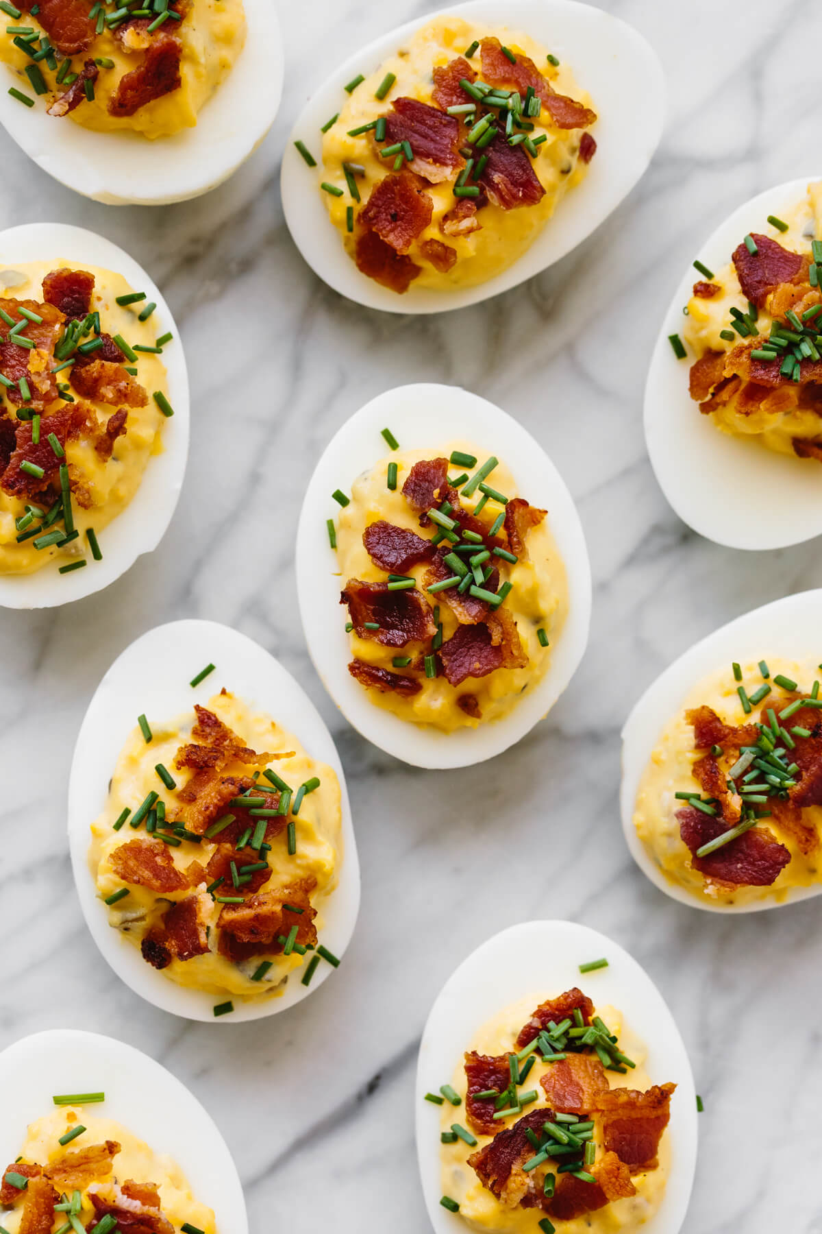 Bacon deviled eggs are the ultimate deviled egg recipe! Several bacon deviled eggs on a marble counter.
