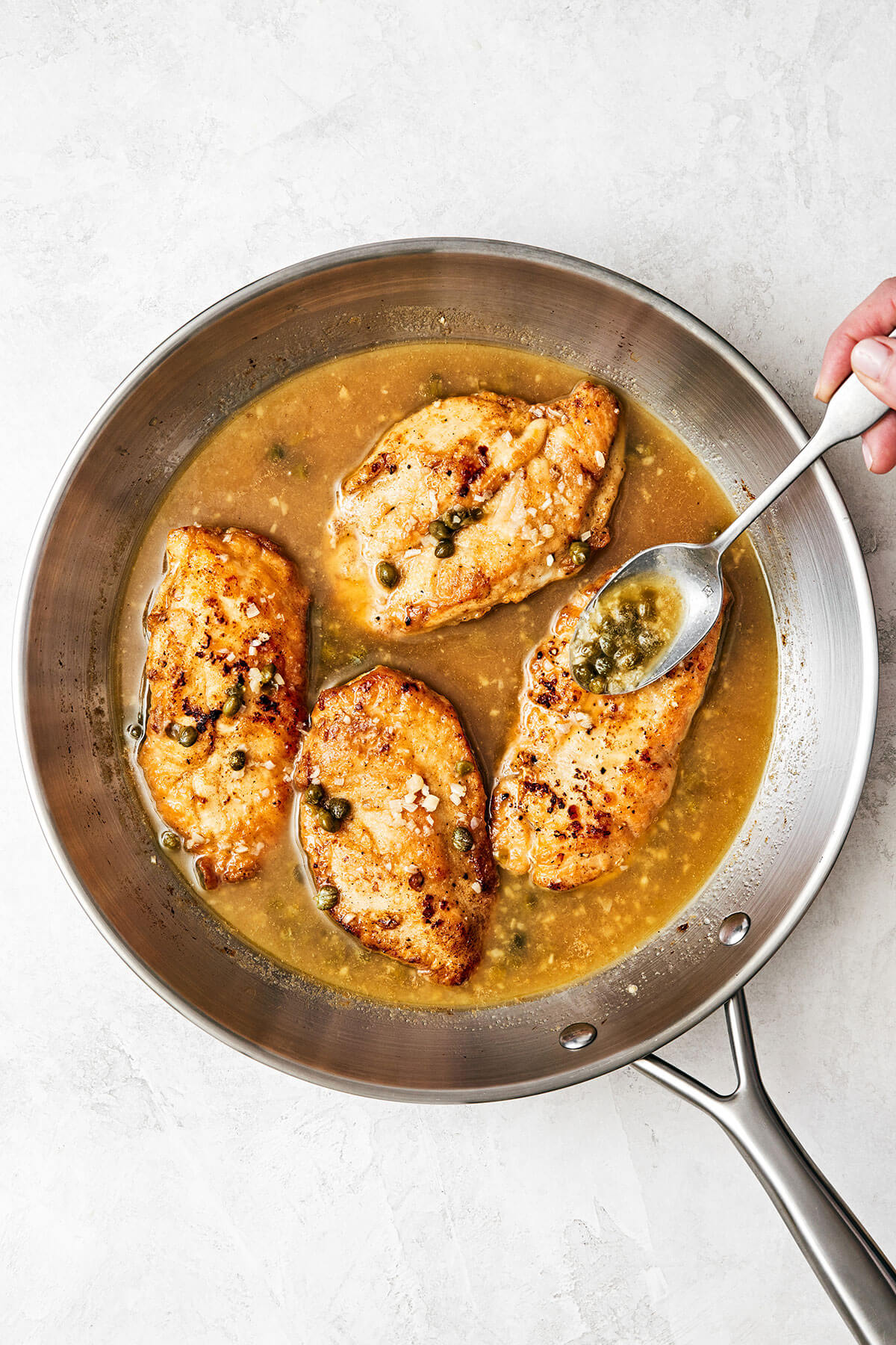 Chicken piccata is the best Italian-American dinner made with golden-crusted chicken breasts simmered in a lemon garlic wine sauce. Chicken piccata in a pan