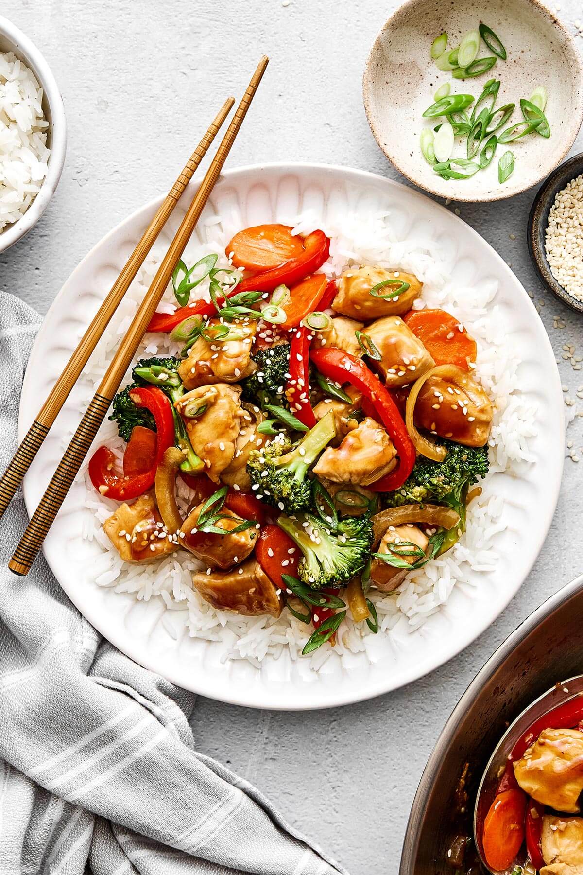 Add another splash of oil, then sauté the bell pepper, onion, carrot, and broccoli until tender, yet crisp. Chicken stir-fry and rice on a plate.