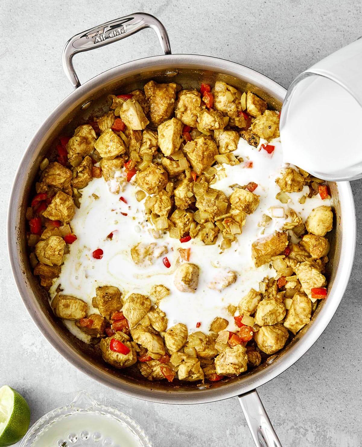 Coconut curry chicken is a cozy one-pan meal that’s packed with comforting flavor. Adding coconut milk into pan with chicken.