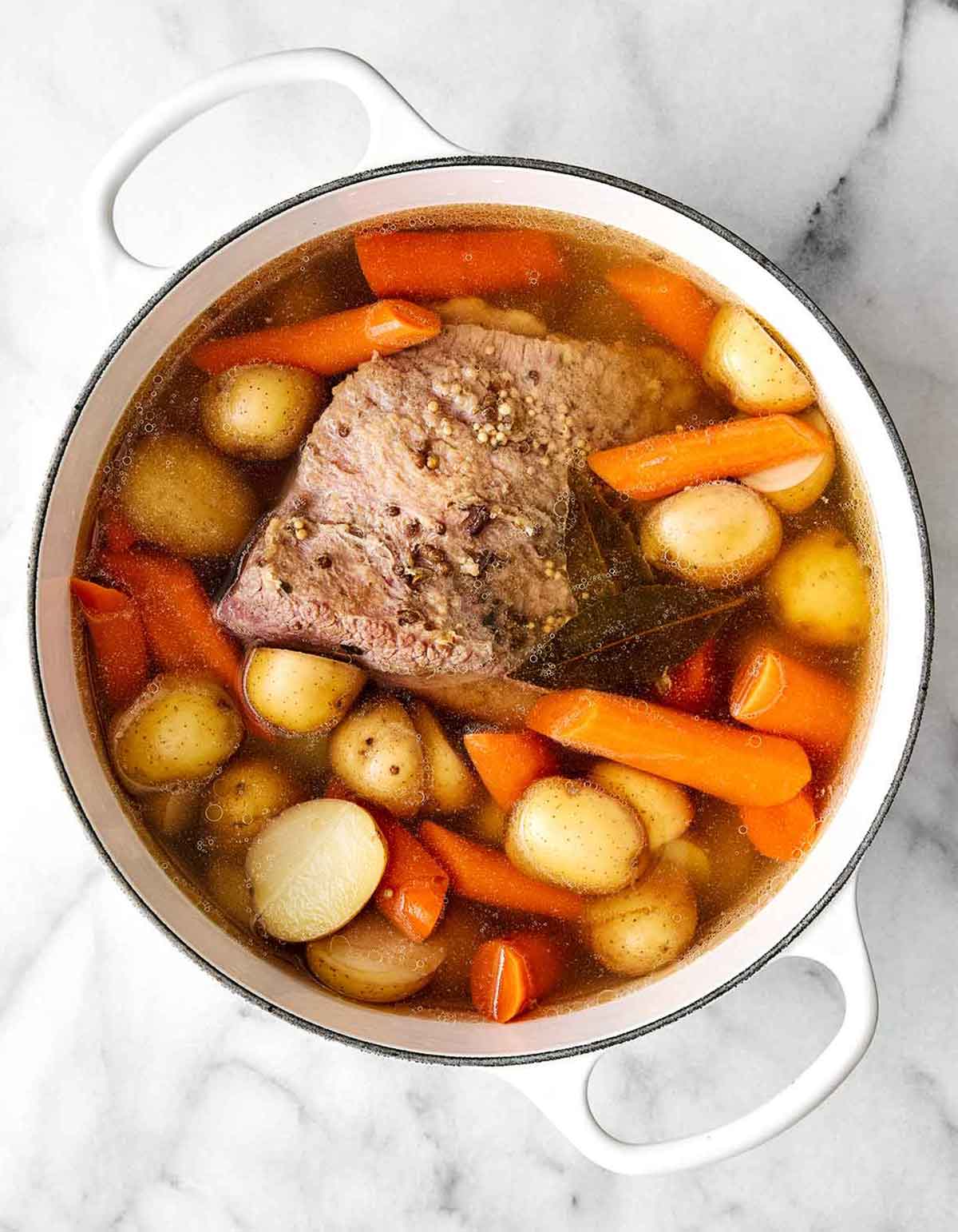Celebrate St. Patrick's Day with the best corned beef and cabbage! Juicy brisket, creamy horseradish sauce, and hearty veggies. Step two of corned beef and cabbage: Add the potatoes and carrots.