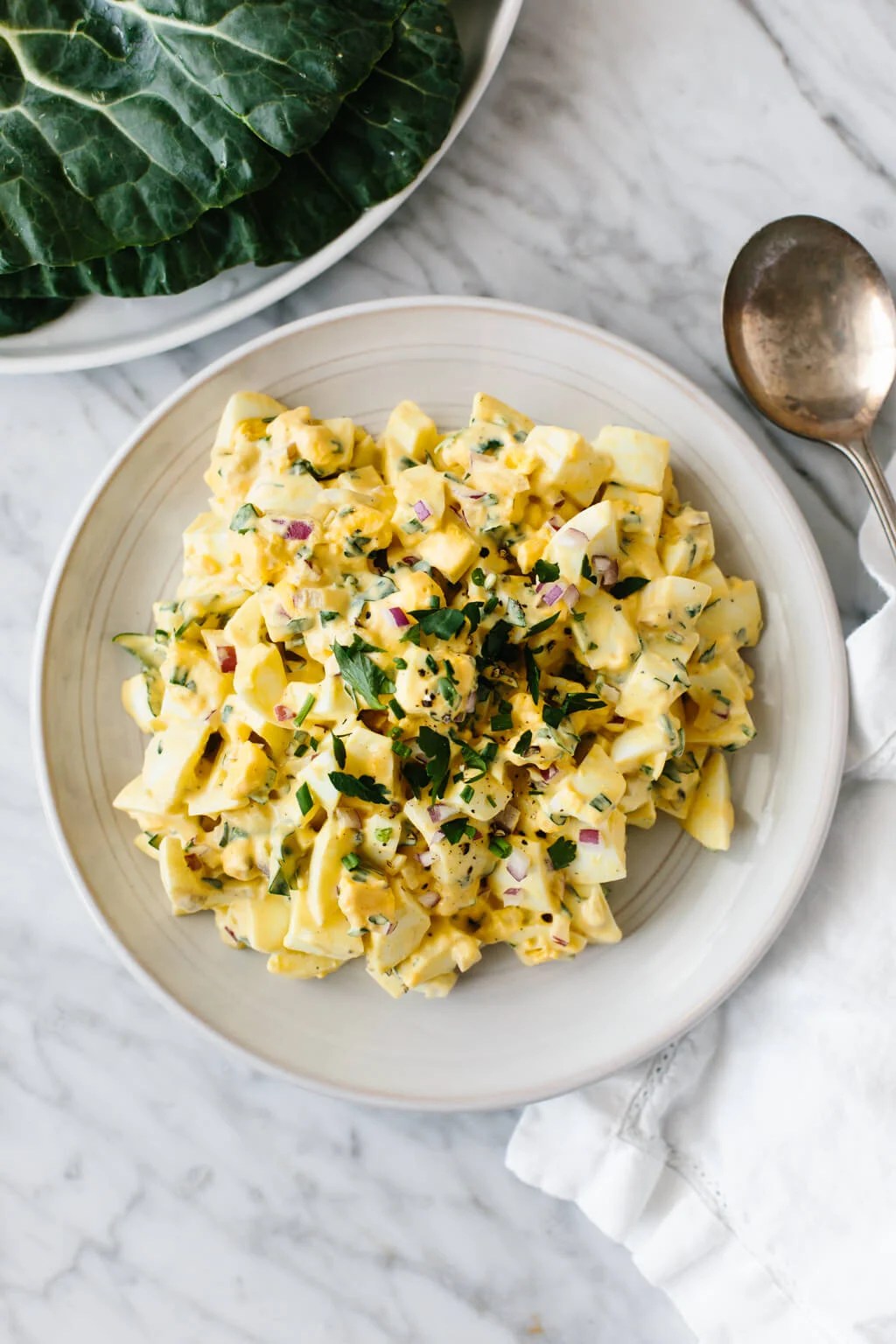 Egg salad on a white plate on a marble background.