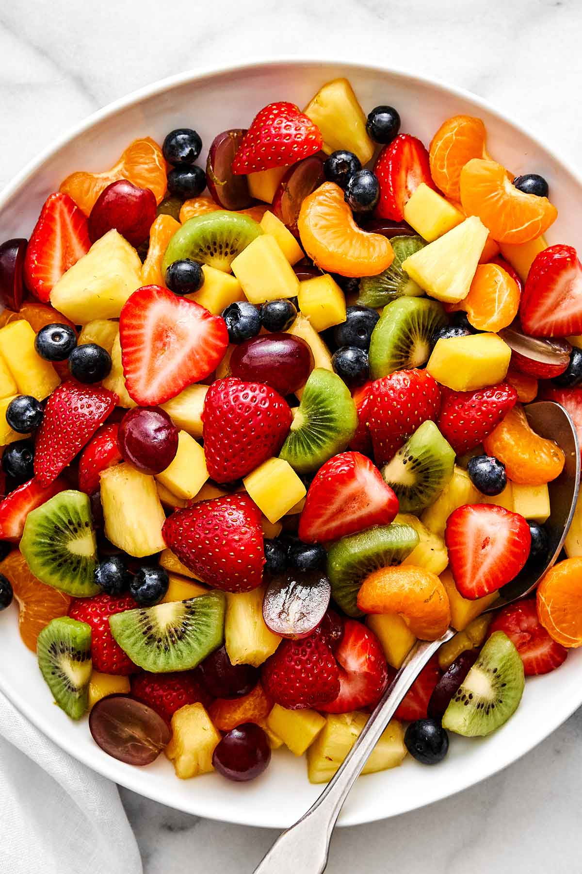 A crowd-favorite fruit salad for BBQs and potlucks! It's incredibly simple with juicy seasonal fruit tossed in a honey lime dressing. Fruit salad recipe.