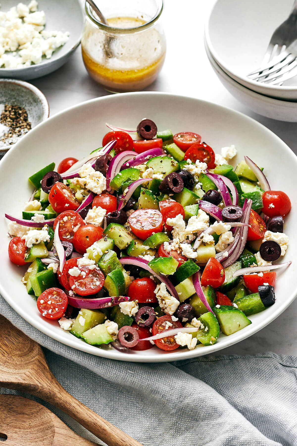 Greek salad is easy to make and bursting with flavor. With only six ingredients, it's one of the best healthy salad recipes! Greek salad in a white bowl next to dressing.