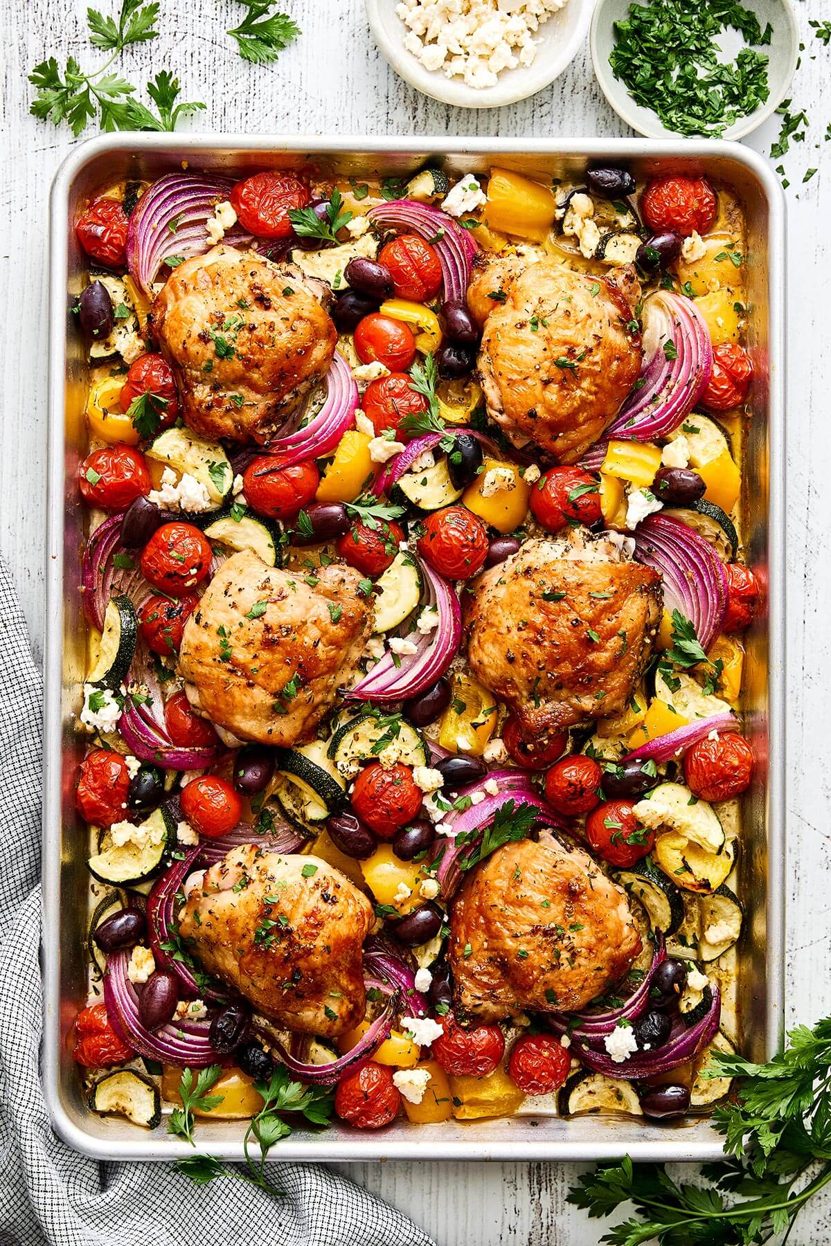 This Greek sheet pan chicken is an easy, all-in-one dinner recipe with juicy chicken thighs nestled around vibrant, Mediterranean vegetables. Greek sheet pan chicken.