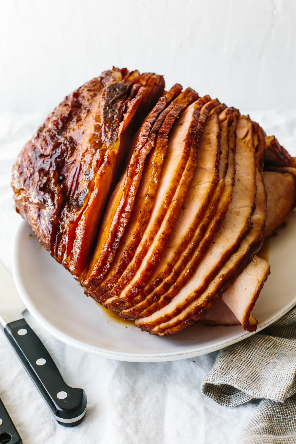 A homemade honey baked ham (with the best honey glaze) that's an easy, foolproof holiday main? We're all for that here! Honey baked ham on a plate next to a knife