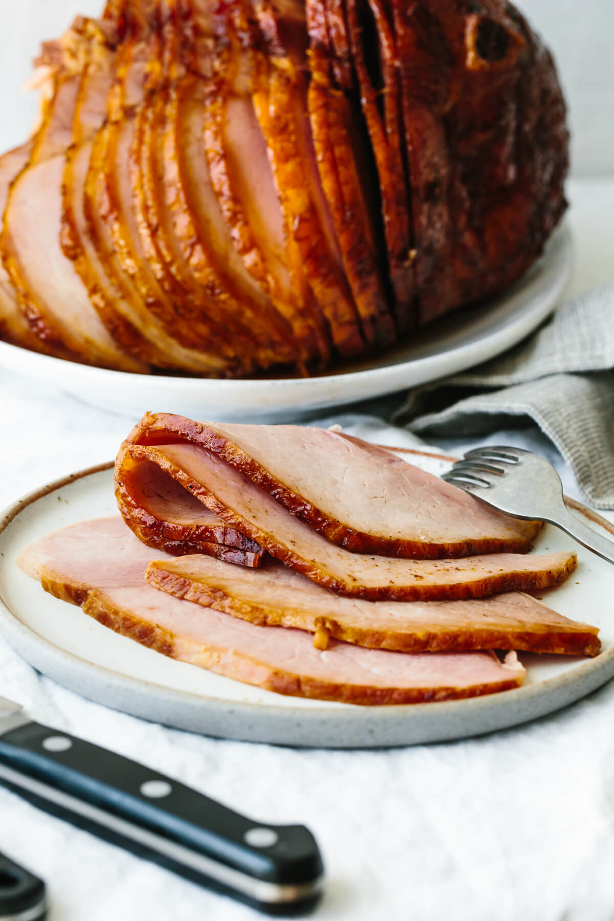 A homemade honey baked ham (with the best honey glaze) that's an easy, foolproof holiday main? We're all for that here! Sliced honey baked ham on a plate with a fork
