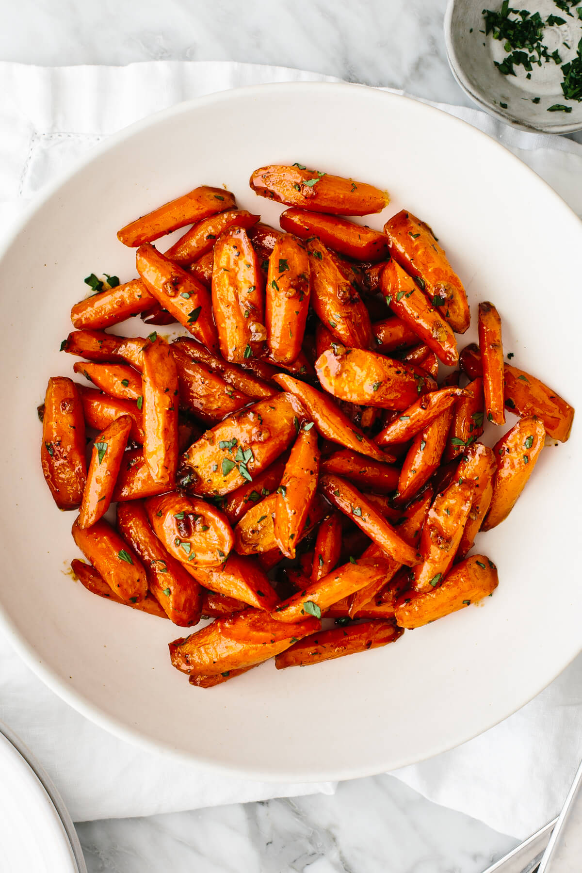 Honey glazed carrots in a white bowl on a table.