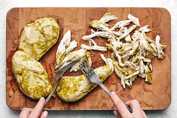 Shredding salsa verde chicken with forks.
