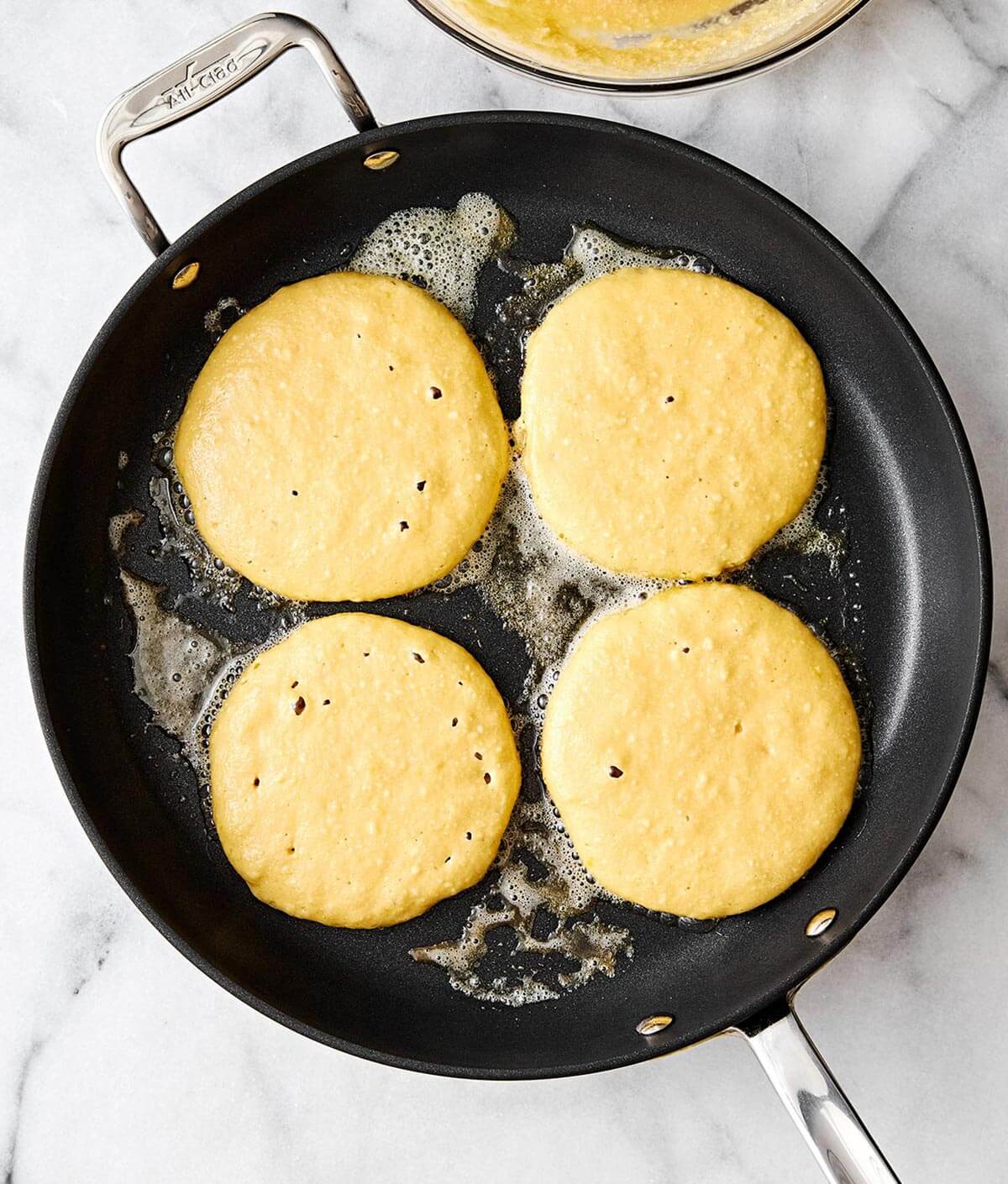 These fluffy lemon ricotta protein pancakes are a sweet and delicious way to incorporate more protein into your breakfast routine! Cooking protein pancakes in a pan.