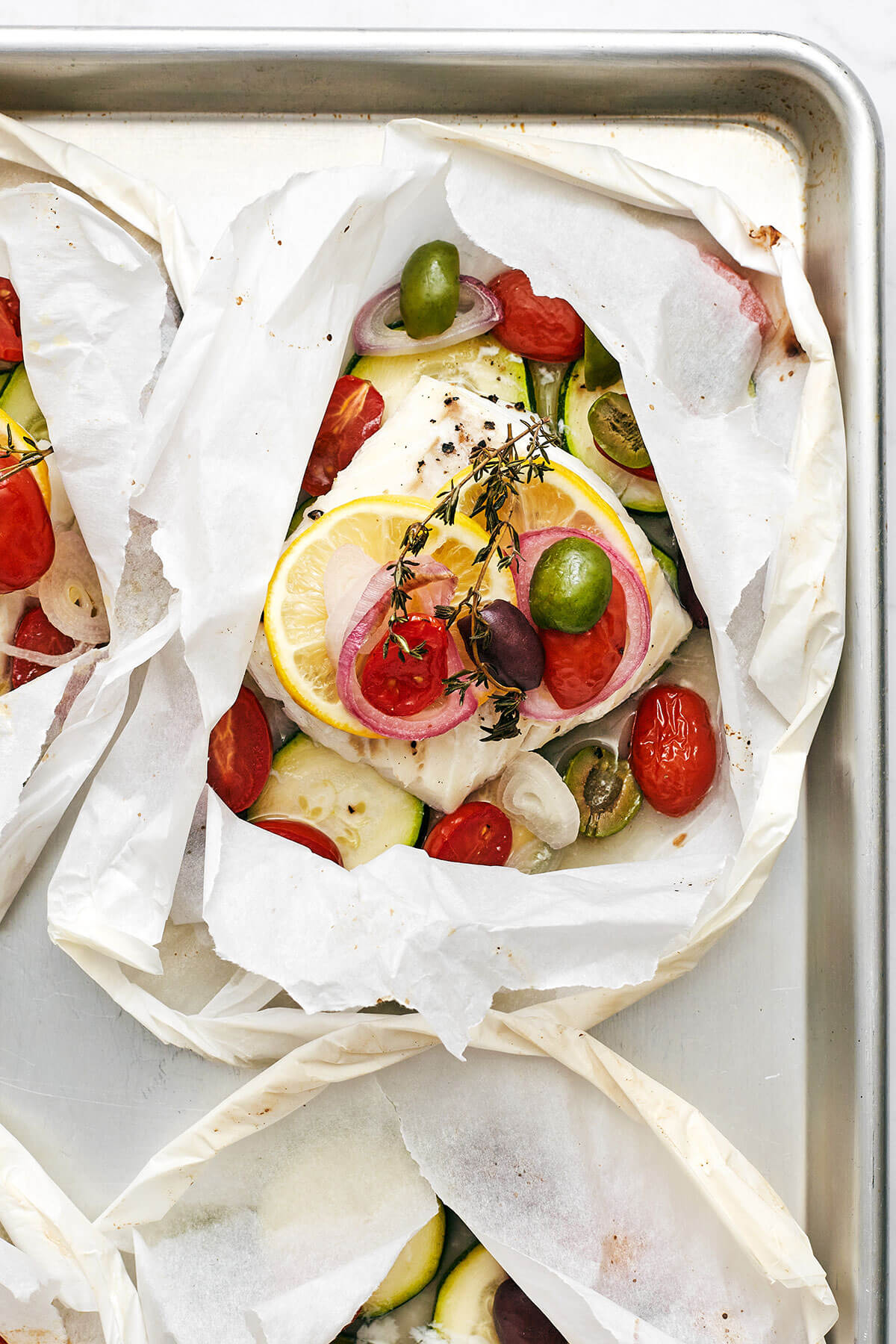 This Mediterranean cod en papillote is the most genius way to quickly achieve a simple, healthy, and super delicious dinner! Cod en papillote wrapped on a baking sheet