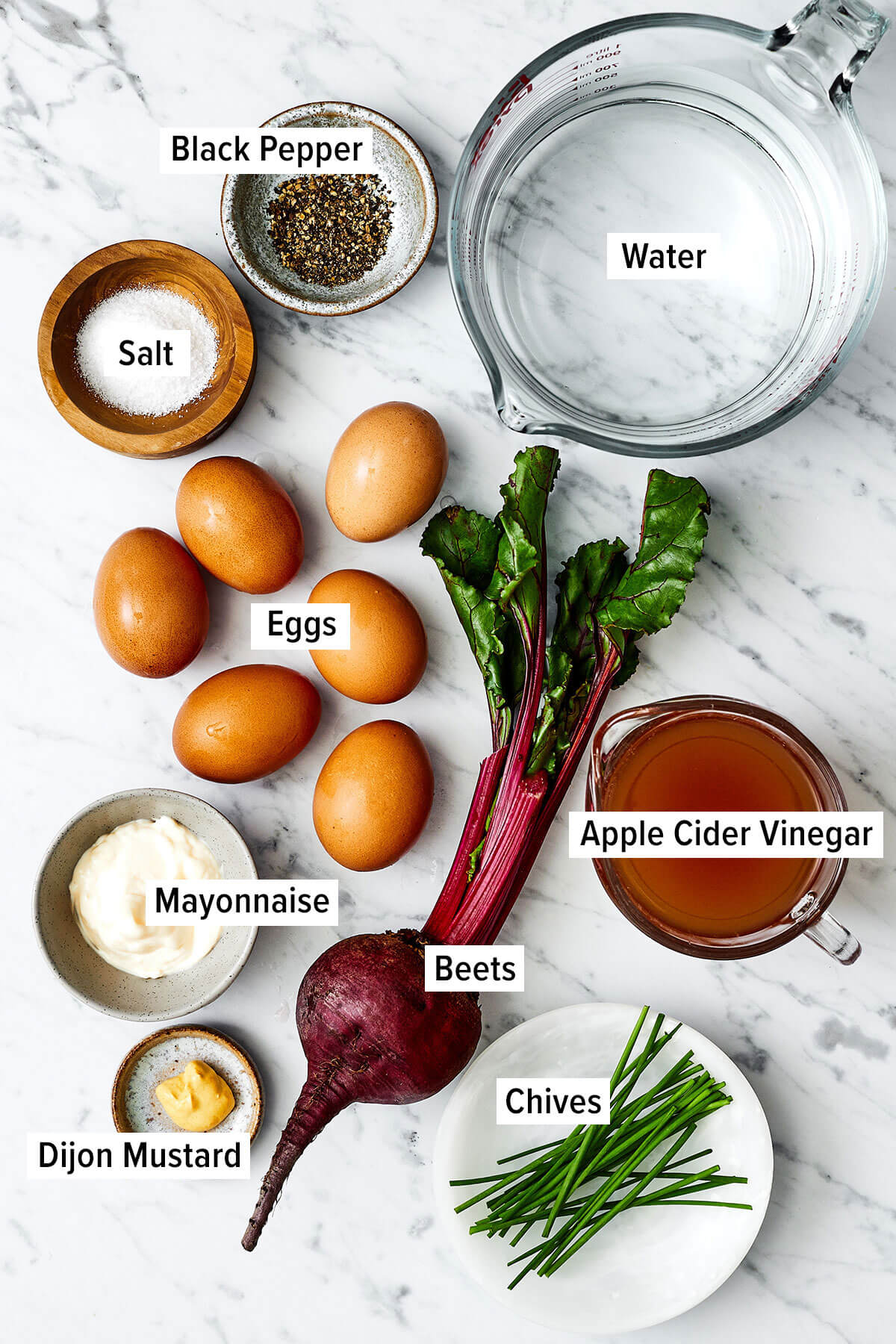 Step up your appetizer game with beet pickled deviled eggs! They're stained to a beautiful red, taste delicious, and are perfect for Easter. Ingredients for beet pickled deviled eggs on a table