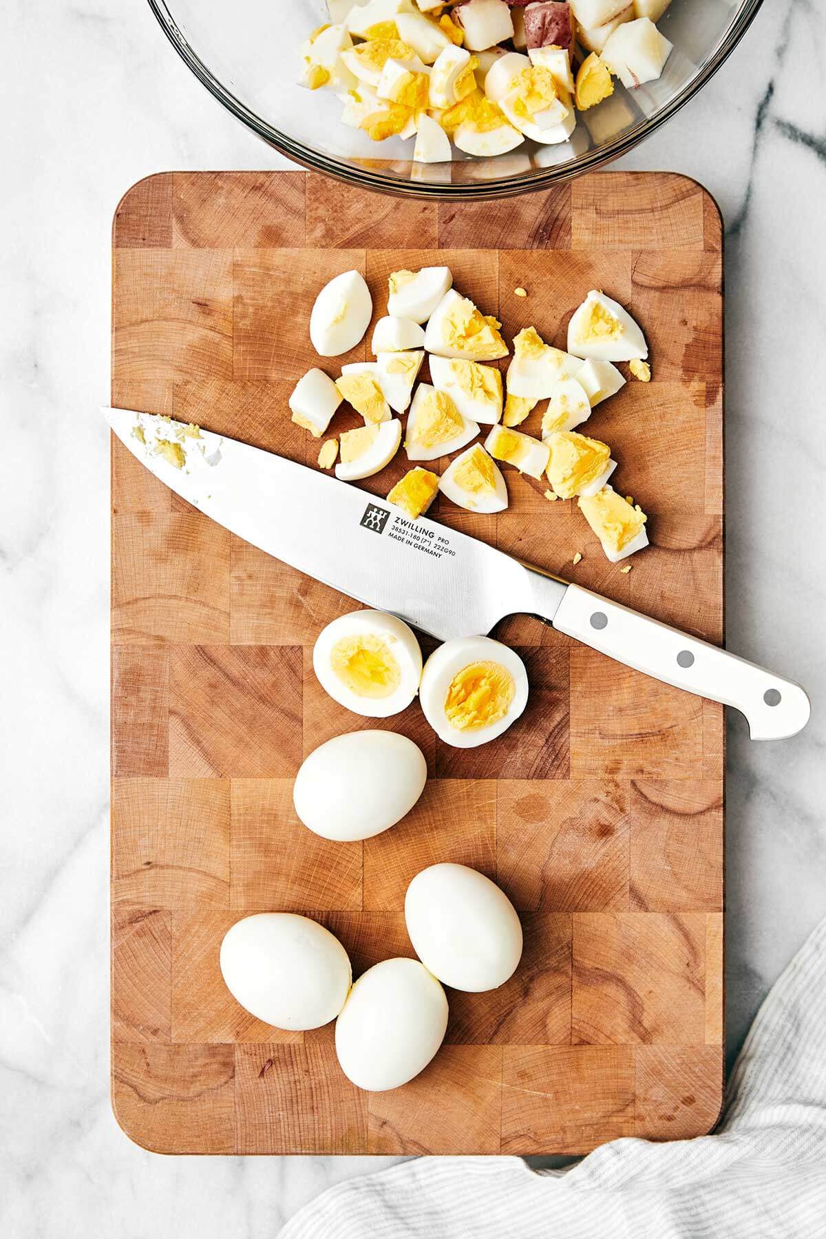 This classic potato salad recipe with eggs and red potatoes is easy, flavorful, and loaded with texture. It's the perfect summer side dish for BBQ's, picnics, and dinner parties! Diced eggs on a wooden board.