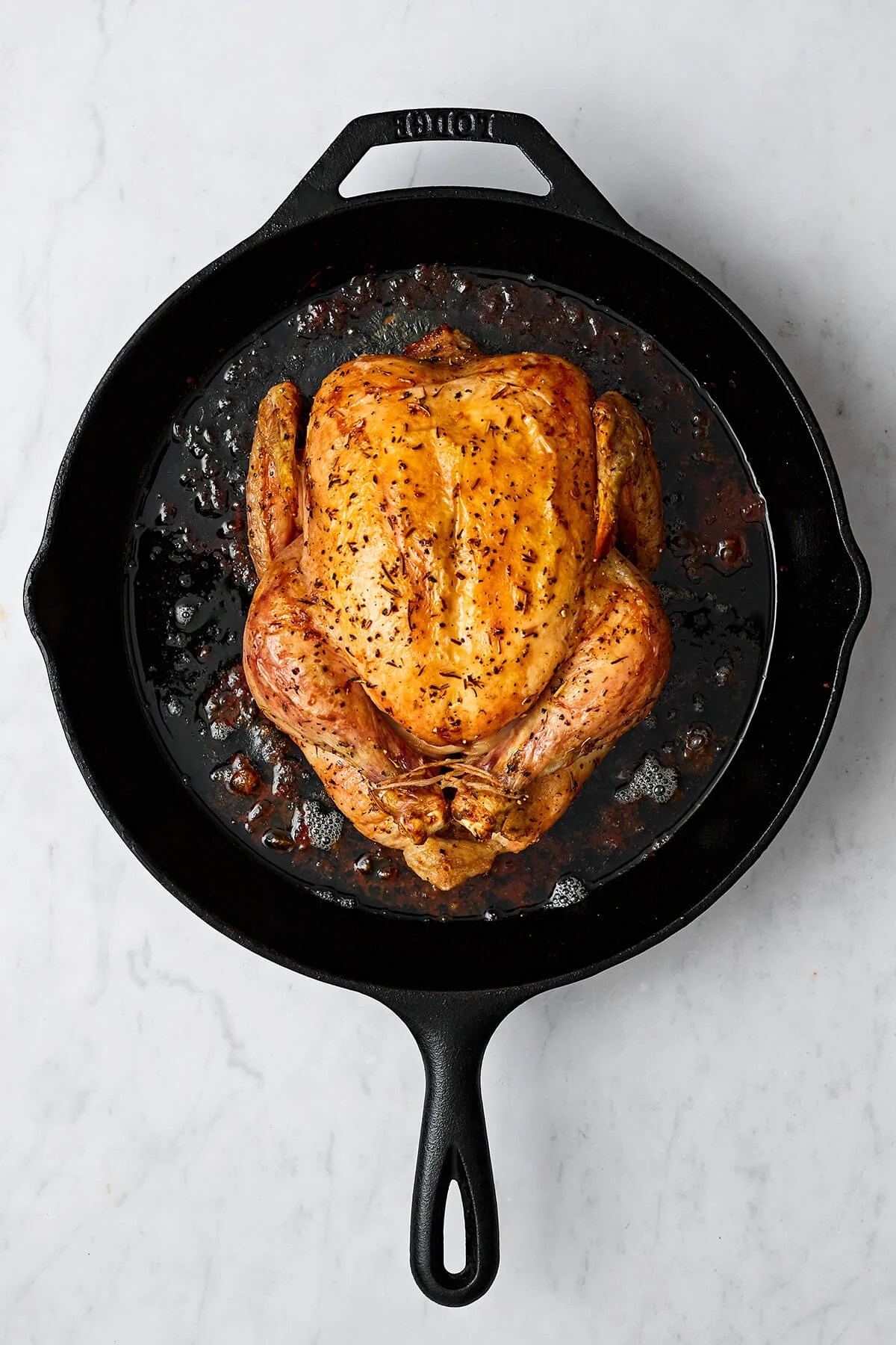 Learning how to roast chicken is the ultimate kitchen staple. It's easy to make, feeds a surplus, and can be served in dozens of ways! A cooked whole roasted chicken in a skillet