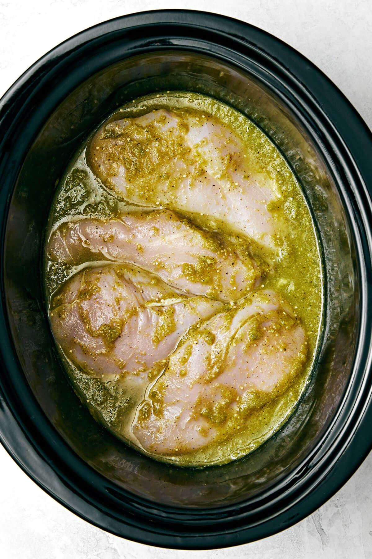 This salsa verde chicken is juicy, tender, and brimming with smoked, tangy, and spicy flavors. Plus, it's made easy right in the slow cooker! Chicken with salsa verde in a slow cooker.