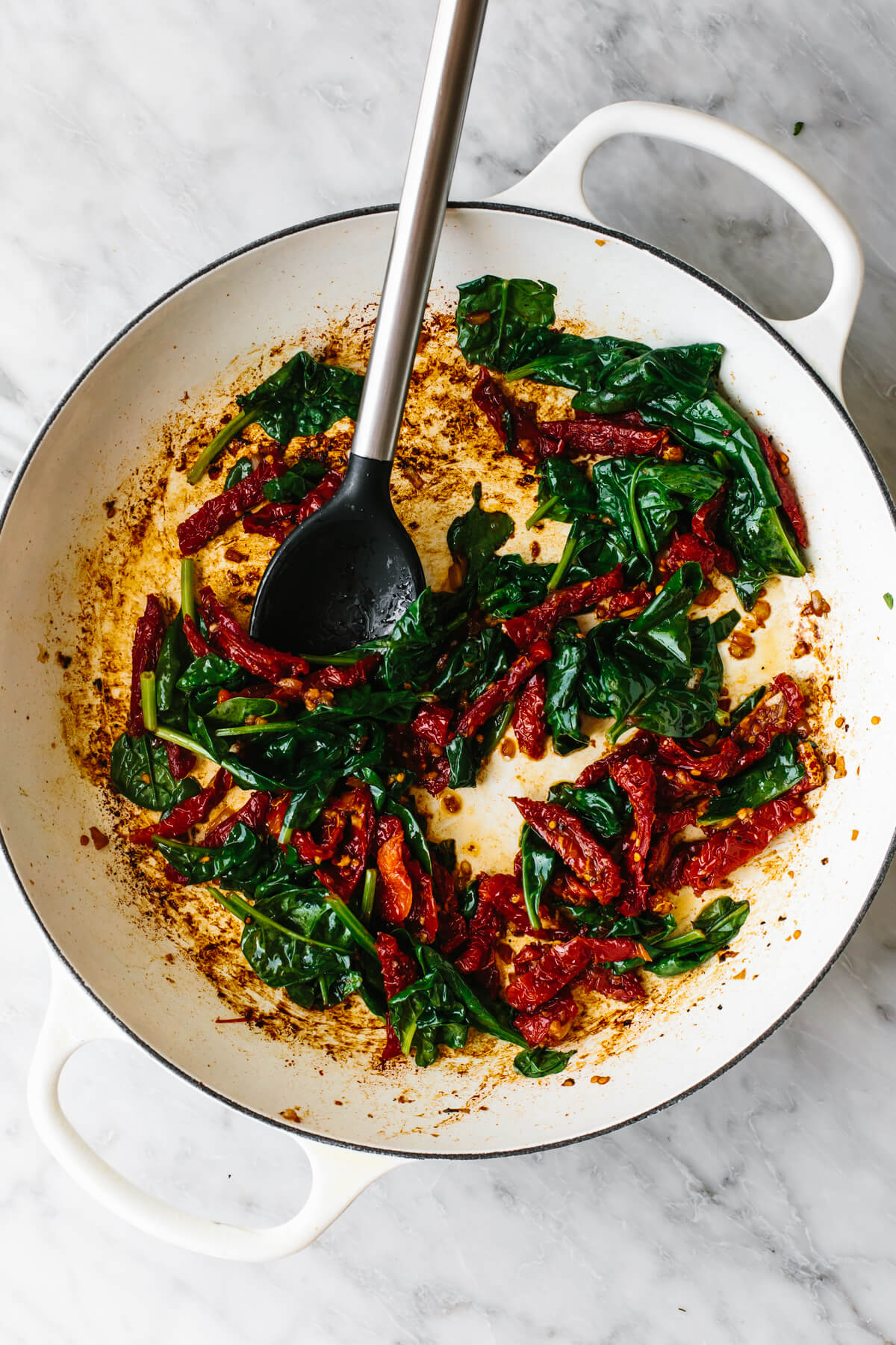 Steal hearts with this creamy tuscan chicken recipe! Seared Italian chicken simmers in a rich and creamy, spinach and sun-dried tomato sauce. Cooking spinach and tomatoes in a skillet for tuscan chicken